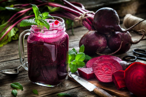 A glass of freshly squeezed red beetroot juice next to raw organic beetroots, highlighting blood pressure-lowering inorganic nitrates.
